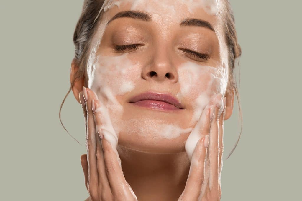 Femme qui se lave le visage avec du savon