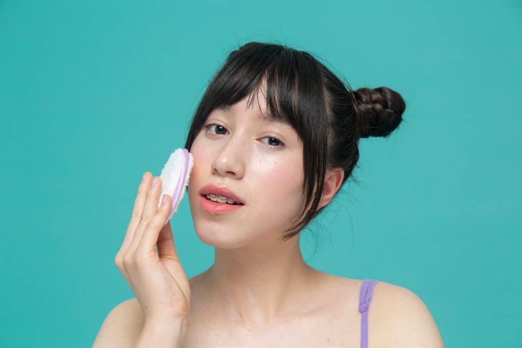 Femme sui se nettoyant le visage avec un coton réutilisable