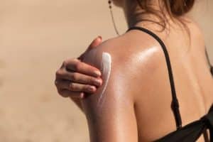 femme qui se met de la crème soleil sur le corps pour protéger sa peau du soleil